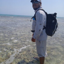 man in fishing gear wading into ocean