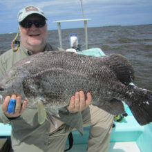man in sunglasses holding large fish on a boat