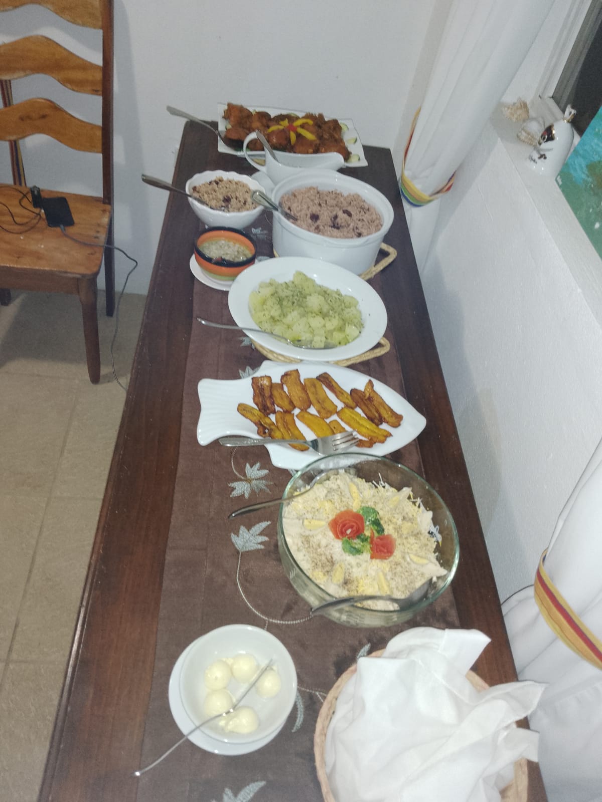 table with plates of rice, beans, and stewed chicken